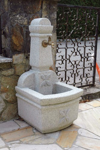 Netter Brunnen mit Wasserhahn und Verzierung.