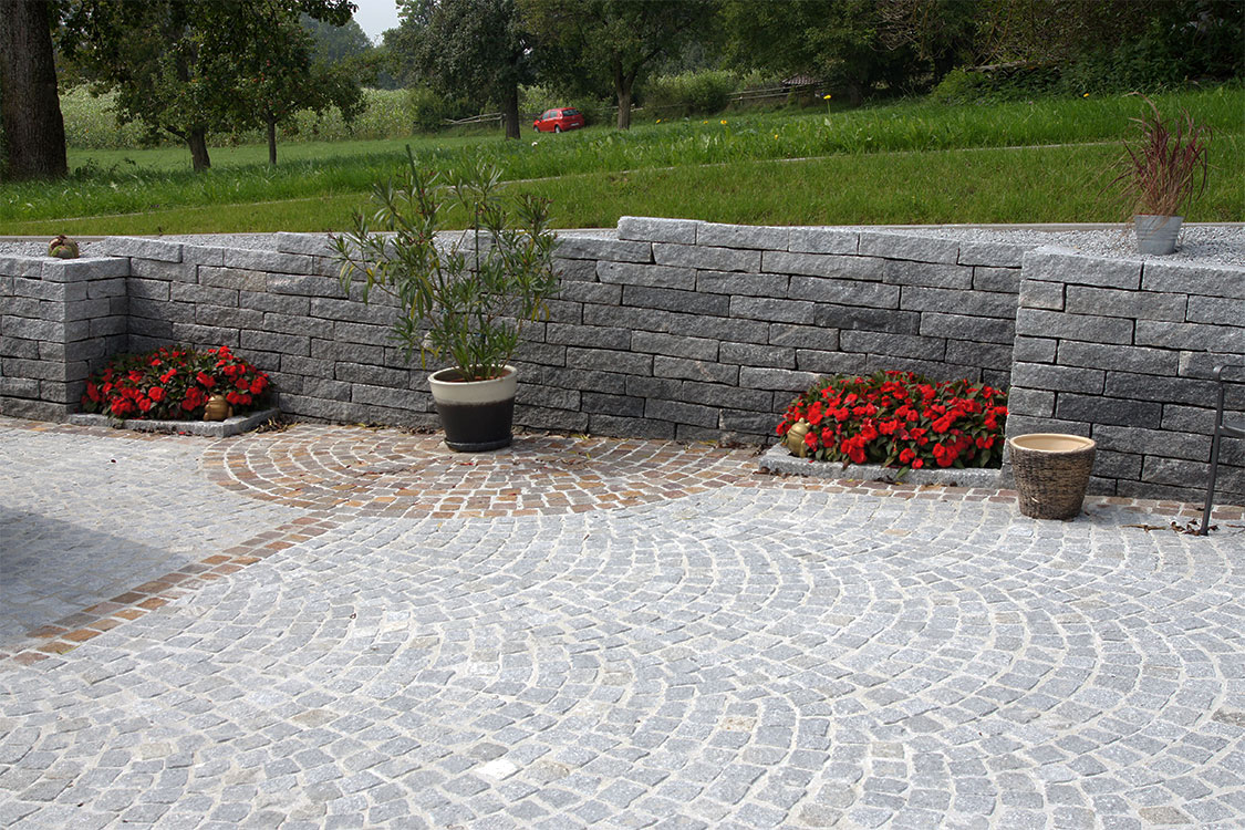 Gepflasterter Granit Platz mit Mauer.